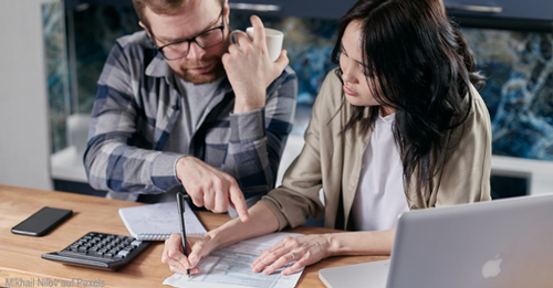 Finanzplan - Zwei Personen sortieren Rechnungen, Kontoauszüge und Finanzunterlagen an einem Tisch