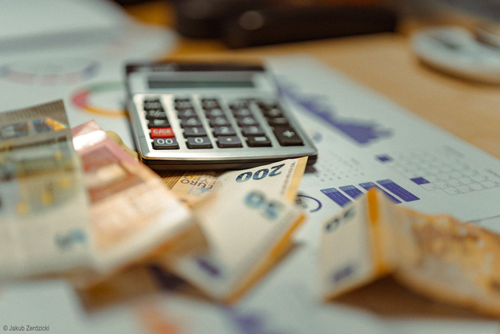 Euro-Banknoten und Taschenrechner auf Finanzunterlagen zur Budgetplanung